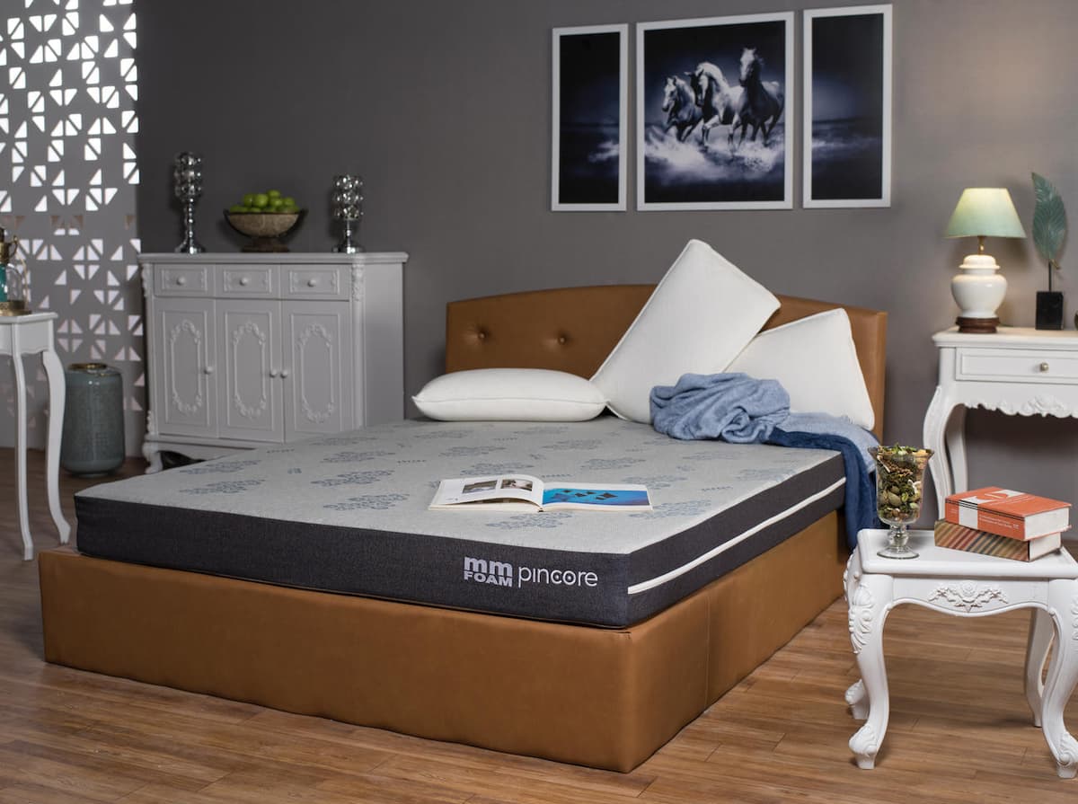 An MM Foam Pincore mattress made up on a bed, the pin-core latex construction named along the border of the cover