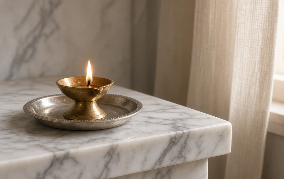 A marble plinth edge with a brass lamp standing on a tray.
