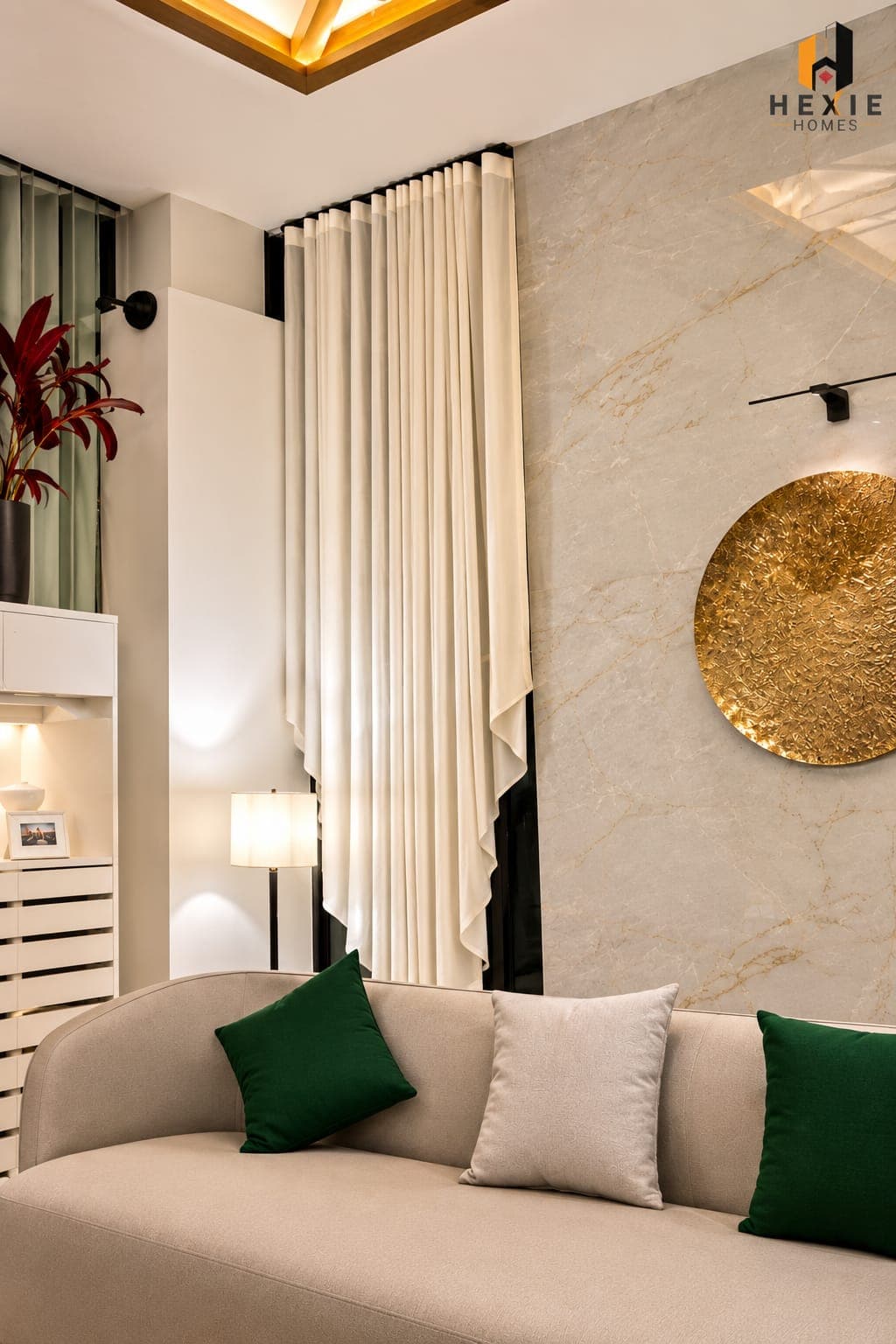 A tall cream curtain drawn back beside a marble wall in a Lore Resorts and Conventions lounge, with a low sofa and green cushions in front of it.