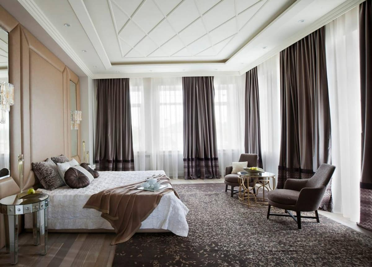 A bedroom window on two tracks — a sheer against the glass, heavier lined curtains in front of it