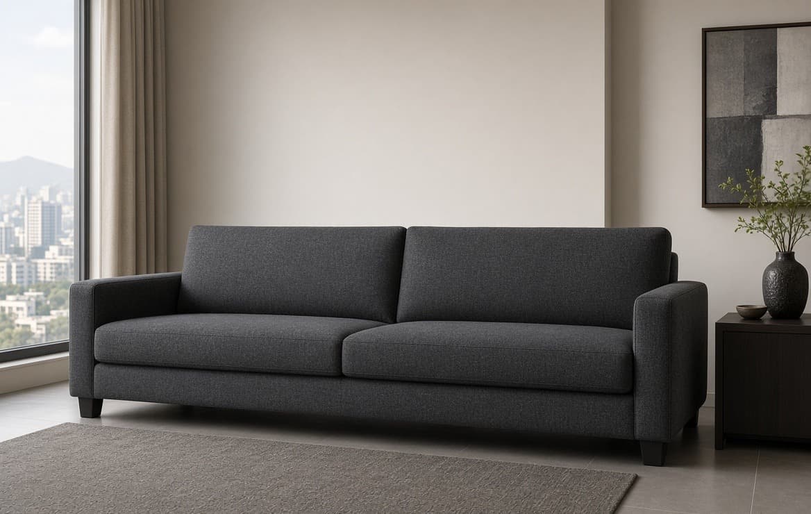 A charcoal tuxedo-back three-seat, arms level with the back, against a plain wall